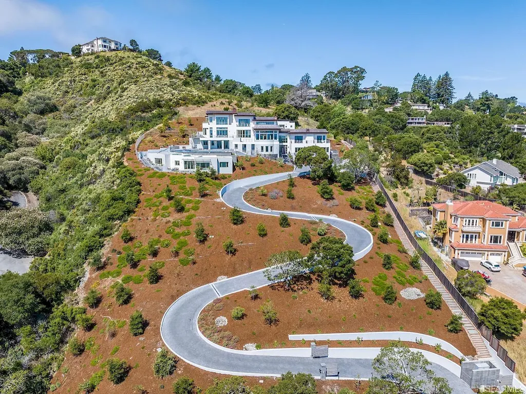 165 Woodridge Road Home in Hillsborough, California. Situated on 2.19 acres, this brand new state-of-the-art construction in Northern California boasts unobstructed, panoramic views as far as the eye can see. The architectural marvel features 26-ft high curved ceilings, rounded walls, and floor-to-ceiling windows, bathing the interior in natural light and showcasing breathtaking 180-degree bay and canyon vistas. Step onto the stunning limestone terrace, where a curved pool with a dancing water feature, spa, built-in Kalamazoo bbq station, outdoor shower, and access to a luxurious 2-bedroom, 2-bath guest house await. 