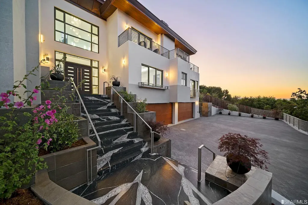 165 Woodridge Road Home in Hillsborough, California. Situated on 2.19 acres, this brand new state-of-the-art construction in Northern California boasts unobstructed, panoramic views as far as the eye can see. The architectural marvel features 26-ft high curved ceilings, rounded walls, and floor-to-ceiling windows, bathing the interior in natural light and showcasing breathtaking 180-degree bay and canyon vistas. Step onto the stunning limestone terrace, where a curved pool with a dancing water feature, spa, built-in Kalamazoo bbq station, outdoor shower, and access to a luxurious 2-bedroom, 2-bath guest house await. 