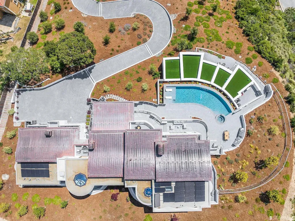 165 Woodridge Road Home in Hillsborough, California. Situated on 2.19 acres, this brand new state-of-the-art construction in Northern California boasts unobstructed, panoramic views as far as the eye can see. The architectural marvel features 26-ft high curved ceilings, rounded walls, and floor-to-ceiling windows, bathing the interior in natural light and showcasing breathtaking 180-degree bay and canyon vistas. Step onto the stunning limestone terrace, where a curved pool with a dancing water feature, spa, built-in Kalamazoo bbq station, outdoor shower, and access to a luxurious 2-bedroom, 2-bath guest house await. 