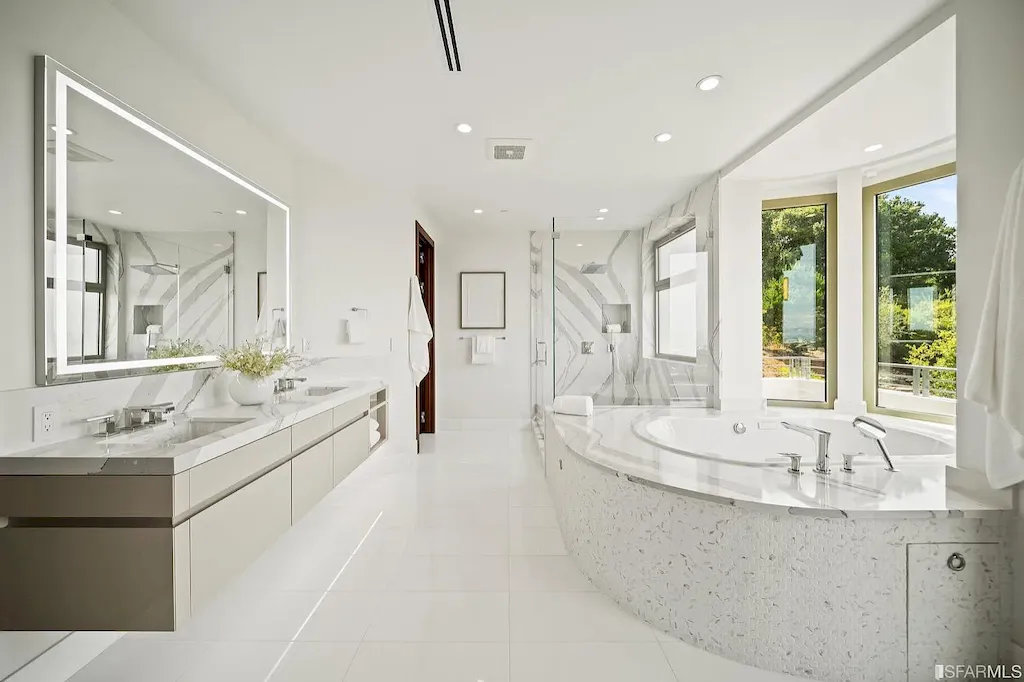 165 Woodridge Road Home in Hillsborough, California. Situated on 2.19 acres, this brand new state-of-the-art construction in Northern California boasts unobstructed, panoramic views as far as the eye can see. The architectural marvel features 26-ft high curved ceilings, rounded walls, and floor-to-ceiling windows, bathing the interior in natural light and showcasing breathtaking 180-degree bay and canyon vistas. Step onto the stunning limestone terrace, where a curved pool with a dancing water feature, spa, built-in Kalamazoo bbq station, outdoor shower, and access to a luxurious 2-bedroom, 2-bath guest house await. 