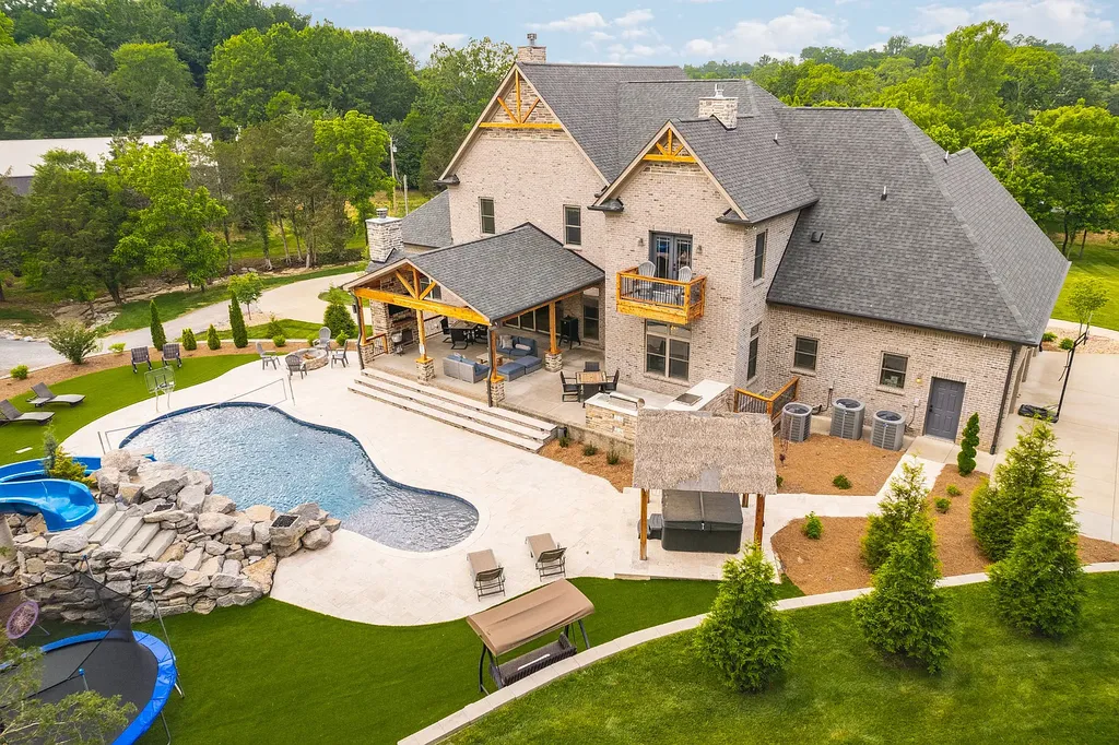5078 Central Pike Home in Mount Juliet, Tennessee. Discover the epitome of luxury living in this stunning custom home situated on nearly 8 acres in Wilson County. Boasting a spacious floor plan, this residence features 5 bedroom suites, a workout room, a hobby room/office, and an outdoor entertaining area complete with a kitchen, custom pool, hot tub, and fire pit. Step into the indoor kitchen, which showcases leathered granite and quartz countertops, as well as a walk-in pantry. The main level and master bath offer the comfort of heated tile flooring.