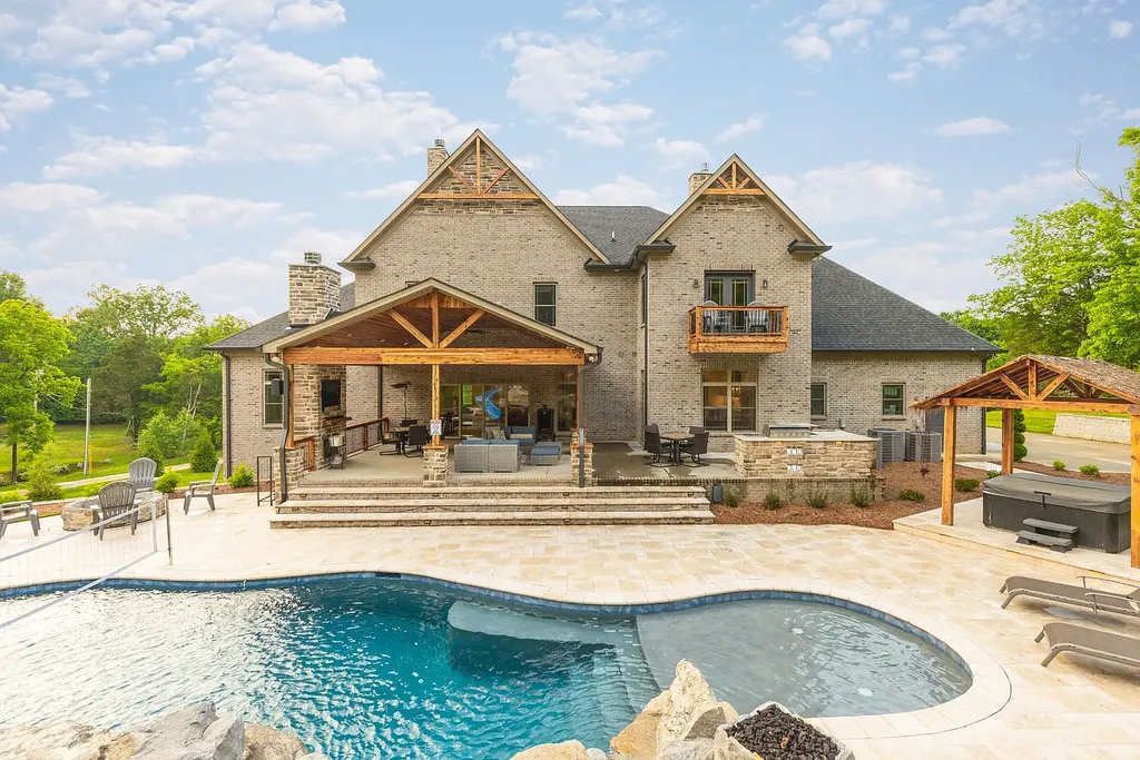 5078 Central Pike Home in Mount Juliet, Tennessee. Discover the epitome of luxury living in this stunning custom home situated on nearly 8 acres in Wilson County. Boasting a spacious floor plan, this residence features 5 bedroom suites, a workout room, a hobby room/office, and an outdoor entertaining area complete with a kitchen, custom pool, hot tub, and fire pit. Step into the indoor kitchen, which showcases leathered granite and quartz countertops, as well as a walk-in pantry. The main level and master bath offer the comfort of heated tile flooring.
