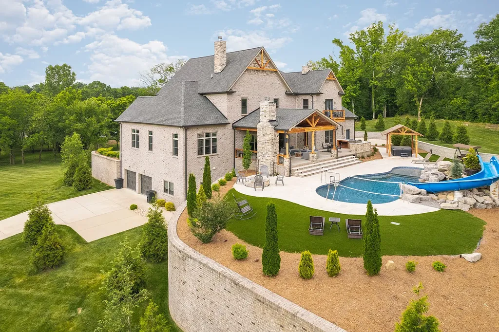 5078 Central Pike Home in Mount Juliet, Tennessee. Discover the epitome of luxury living in this stunning custom home situated on nearly 8 acres in Wilson County. Boasting a spacious floor plan, this residence features 5 bedroom suites, a workout room, a hobby room/office, and an outdoor entertaining area complete with a kitchen, custom pool, hot tub, and fire pit. Step into the indoor kitchen, which showcases leathered granite and quartz countertops, as well as a walk-in pantry. The main level and master bath offer the comfort of heated tile flooring.