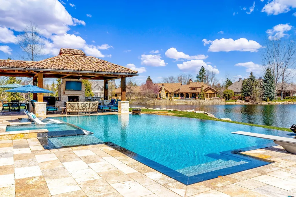 1454 S Heron Pointe Lane Home in Eagle, Idaho. Discover the epitome of luxury and quality in this exceptional Santa Barbara style custom home. Built by renowned Northern Construction and designed by acclaimed architect Trey Hoff, this 1.5-acre waterfront property boasts stunning Spanish Colonial architecture. Step into a world of elegance with an infinity pool, spa, and covered outdoor living area featuring custom sound, heaters, televisions, fireplace, and lighting.