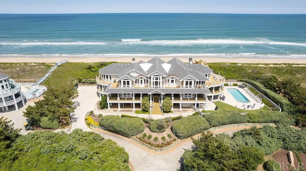 101 Station One Lane Home in Corolla, North Carolina. Discover a remarkable beachfront home with panoramic water views in the prestigious community of Pine Island, Corolla. This stunning coastal retreat offers nine bedrooms with en-suite bathrooms, generous indoor and outdoor amenities, and direct access to 250 feet of secluded beach. 