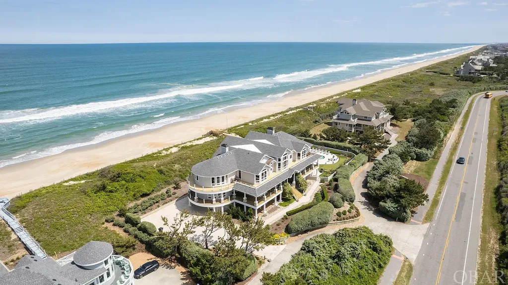 101 Station One Lane Home in Corolla, North Carolina. Discover a remarkable beachfront home with panoramic water views in the prestigious community of Pine Island, Corolla. This stunning coastal retreat offers nine bedrooms with en-suite bathrooms, generous indoor and outdoor amenities, and direct access to 250 feet of secluded beach. 
