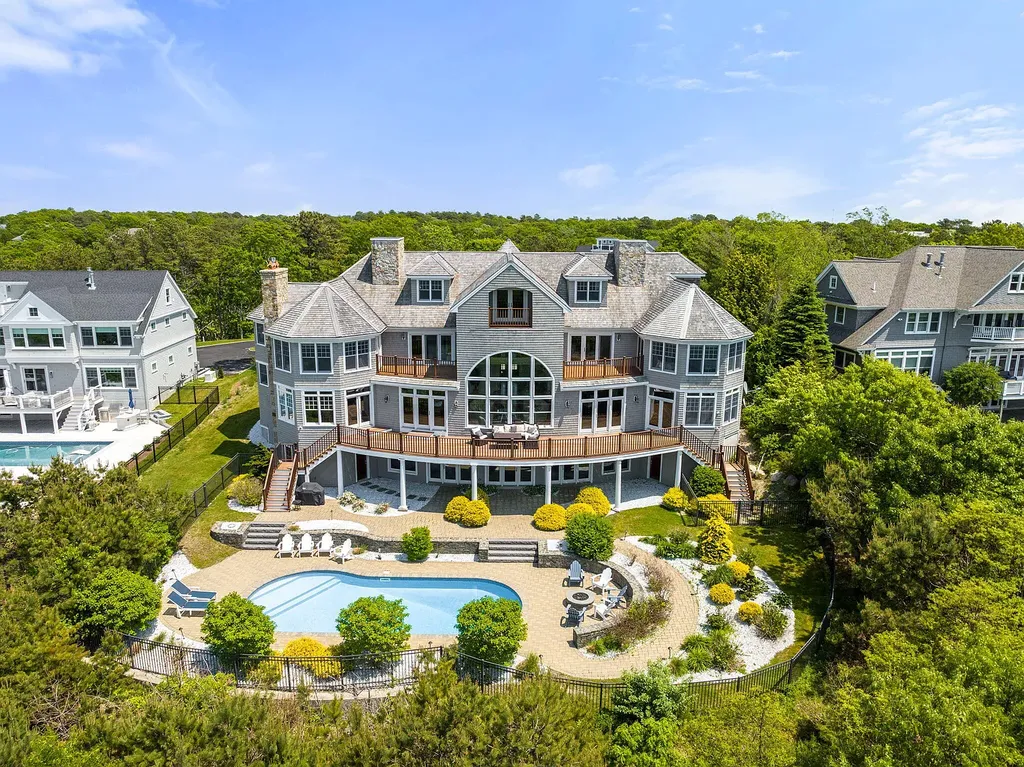 102 Highwood Lane Home in East Falmouth, Massachusetts. Discover unparalleled luxury in Cape Cod's prestigious golf community with this sprawling 10,000-square-foot estate. Perched atop one of Falmouth's highest points, this stunning property offers breathtaking views of Buzzards Bay. Impeccable craftsmanship, elegant design, and high-end finishes define this three-story masterpiece.