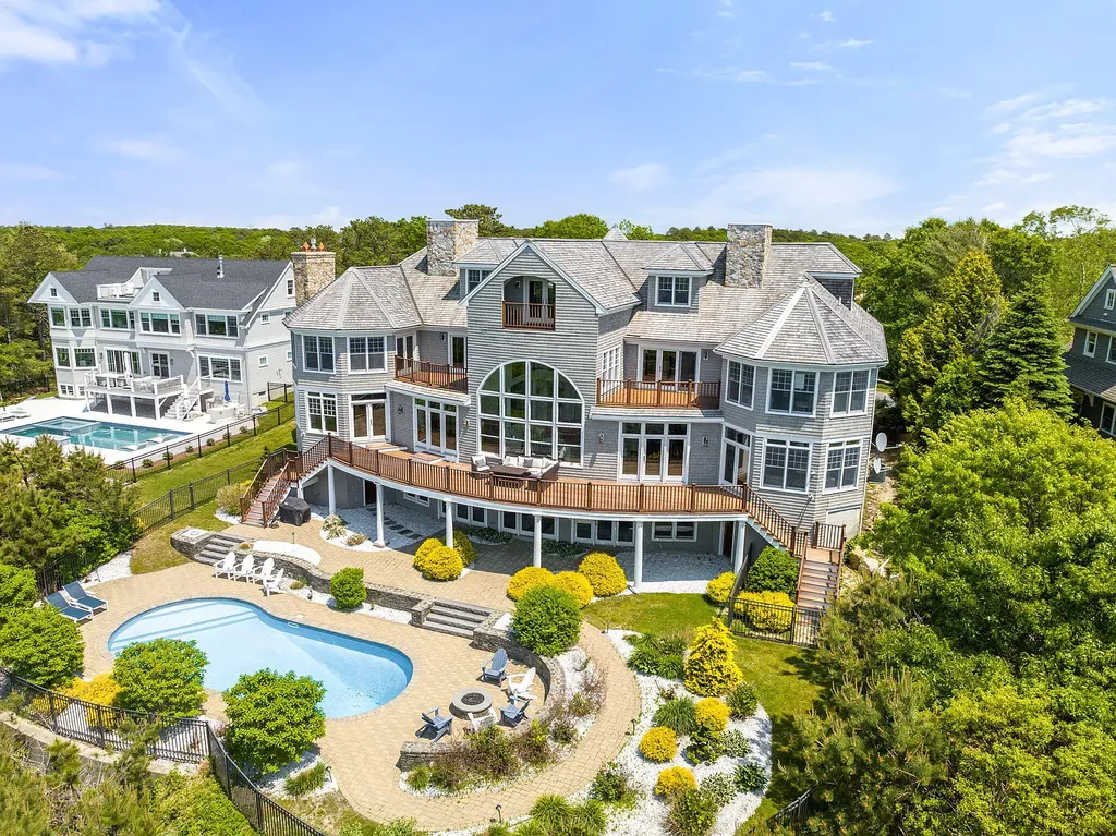 102 Highwood Lane Home in East Falmouth, Massachusetts. Discover unparalleled luxury in Cape Cod's prestigious golf community with this sprawling 10,000-square-foot estate. Perched atop one of Falmouth's highest points, this stunning property offers breathtaking views of Buzzards Bay. Impeccable craftsmanship, elegant design, and high-end finishes define this three-story masterpiece.