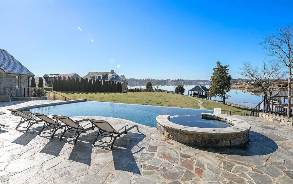 10416 Leonidas Meadow Way Home in Knoxville, Tennessee. Experience the epitome of lakeside luxury in the prestigious West Knoxville enclave of Arcadia. Nestled within this exclusive community, this opulent estate stretches across more than 2.5 acres of prime lakefront property, offering an astonishing 13,000 square feet of meticulously crafted living space. With custom millwork and intricate stonework adorning every corner, this slate and stone residence was artfully constructed with lavishness in mind.