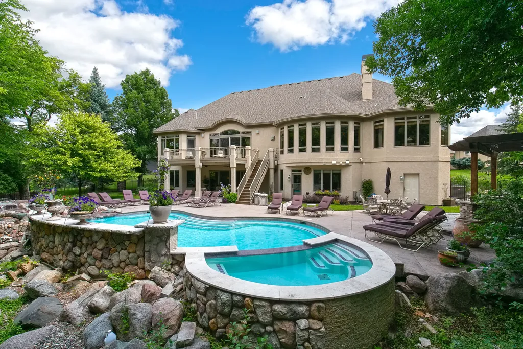 11343 Entrevaux Drive Home in Eden Prairie, Minnesota. Discover the epitome of luxury living in this custom-built Wooddale home, nestled on a serene lot with an extraordinary backyard oasis. The resort-style concrete pool, hot tub, waterfalls, expansive deck, and pergola with a fireplace create an entertainer's dream.
