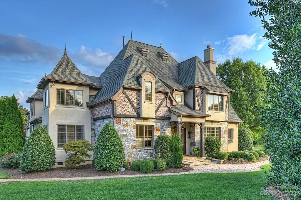 18726 John Connor Road Home in Cornelius, North Carolina. Discover a French-Tudor masterpiece where classic elegance harmoniously merges with contemporary comfort. This estate presents an enchanting façade with steep roofs, tall windows, and intricate wrought iron accents that embody ageless allure.