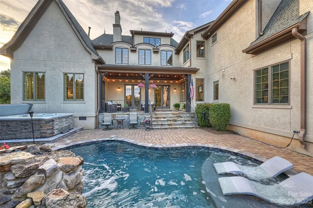 18726 John Connor Road Home in Cornelius, North Carolina. Discover a French-Tudor masterpiece where classic elegance harmoniously merges with contemporary comfort. This estate presents an enchanting façade with steep roofs, tall windows, and intricate wrought iron accents that embody ageless allure.