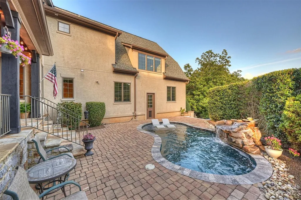 18726 John Connor Road Home in Cornelius, North Carolina. Discover a French-Tudor masterpiece where classic elegance harmoniously merges with contemporary comfort. This estate presents an enchanting façade with steep roofs, tall windows, and intricate wrought iron accents that embody ageless allure.