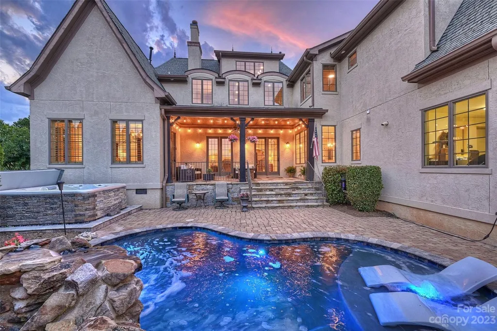 18726 John Connor Road Home in Cornelius, North Carolina. Discover a French-Tudor masterpiece where classic elegance harmoniously merges with contemporary comfort. This estate presents an enchanting façade with steep roofs, tall windows, and intricate wrought iron accents that embody ageless allure.