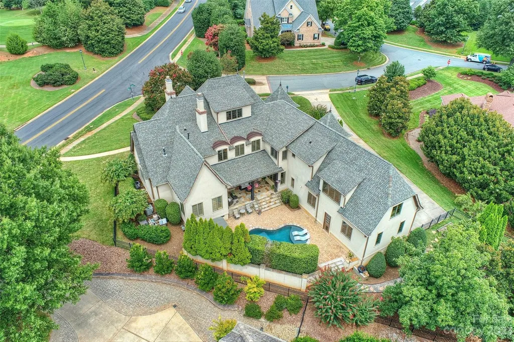 18726 John Connor Road Home in Cornelius, North Carolina. Discover a French-Tudor masterpiece where classic elegance harmoniously merges with contemporary comfort. This estate presents an enchanting façade with steep roofs, tall windows, and intricate wrought iron accents that embody ageless allure.