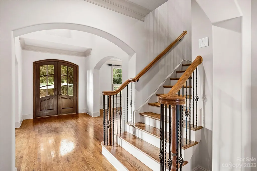 18726 John Connor Road Home in Cornelius, North Carolina. Discover a French-Tudor masterpiece where classic elegance harmoniously merges with contemporary comfort. This estate presents an enchanting façade with steep roofs, tall windows, and intricate wrought iron accents that embody ageless allure.