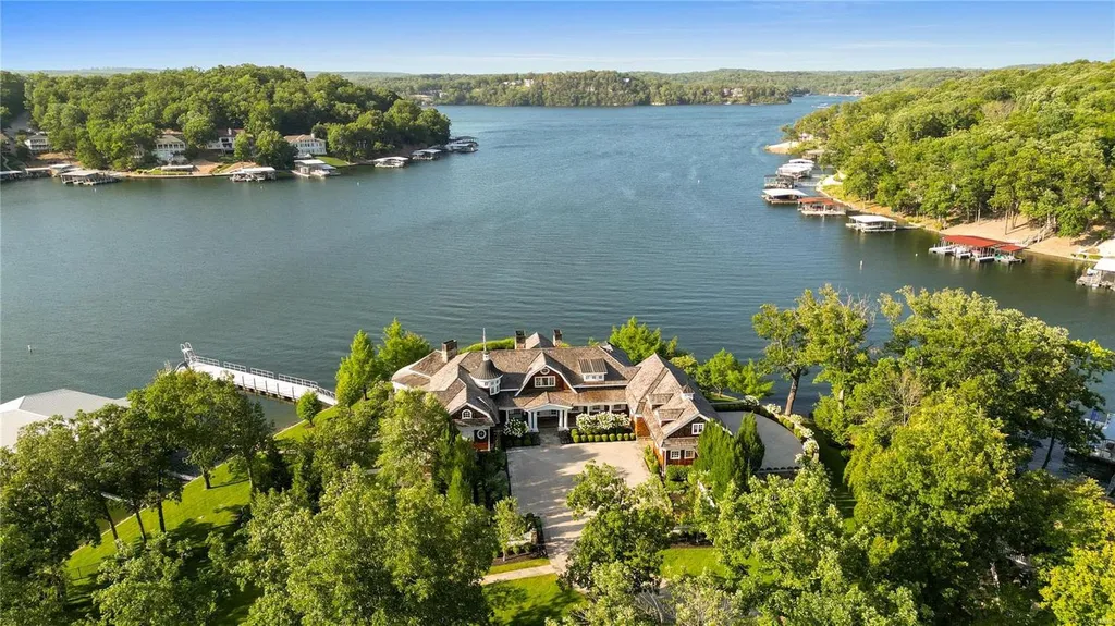 282 Timber Ridge Lane Home in Lake Ozark, Missouri. "Nantucket Point" is the ultimate Crown Jewel of Lake of The Ozarks, offering 1.24 acres of unparalleled beauty with 500' of shoreline, deep water, and breathtaking views. This Nantucket-inspired 6,800 sqft estate exudes laid-back luxury and coastal design, featuring 6 ensuite bedrooms, 2 gourmet kitchens, a gym, game room, and more. 