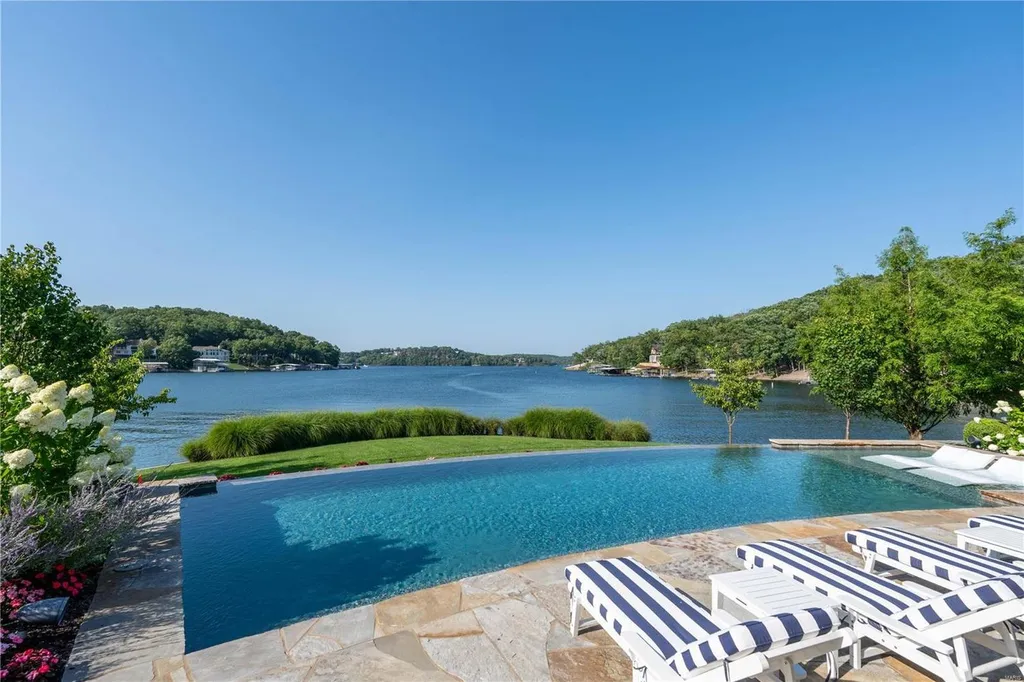 282 Timber Ridge Lane Home in Lake Ozark, Missouri. "Nantucket Point" is the ultimate Crown Jewel of Lake of The Ozarks, offering 1.24 acres of unparalleled beauty with 500' of shoreline, deep water, and breathtaking views. This Nantucket-inspired 6,800 sqft estate exudes laid-back luxury and coastal design, featuring 6 ensuite bedrooms, 2 gourmet kitchens, a gym, game room, and more. 