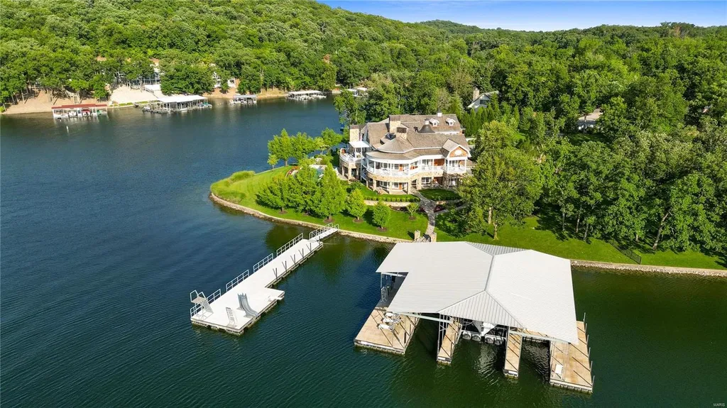 282 Timber Ridge Lane Home in Lake Ozark, Missouri. "Nantucket Point" is the ultimate Crown Jewel of Lake of The Ozarks, offering 1.24 acres of unparalleled beauty with 500' of shoreline, deep water, and breathtaking views. This Nantucket-inspired 6,800 sqft estate exudes laid-back luxury and coastal design, featuring 6 ensuite bedrooms, 2 gourmet kitchens, a gym, game room, and more. 