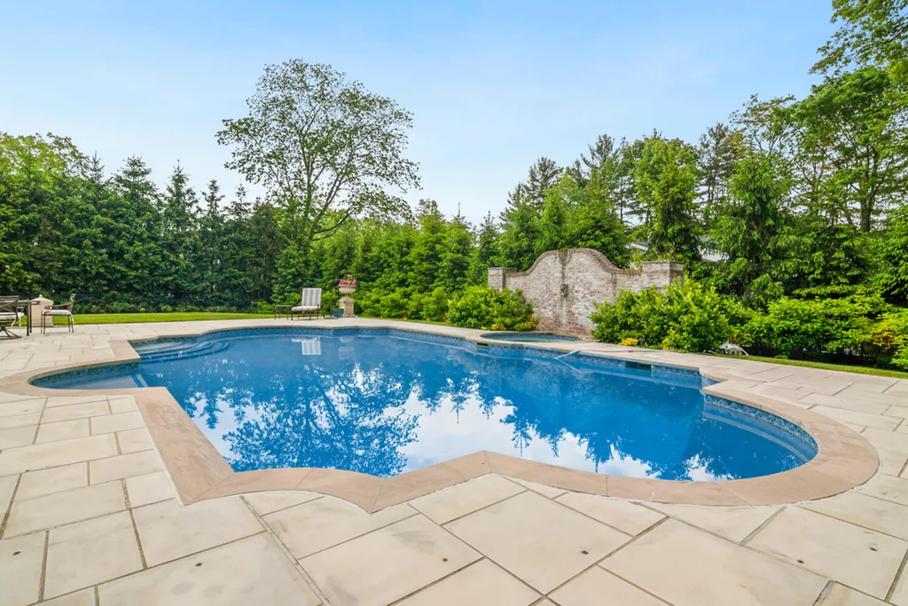 1 Lockhern Drive Home in Livingston Township, New Jersey. Step into the world of opulence with this custom-built, all-brick French Manor nestled on a tranquil cul-de-sac. The mature landscaping, saltwater pool, hot tub, limestone pool deck, and outdoor fireplace spanning 30 feet create a private oasis. Inside, discover a grand entrance hall leading to a stunning living room with a soaring 2-story ceiling, fireplace, and French doors opening to the patio and pool.
