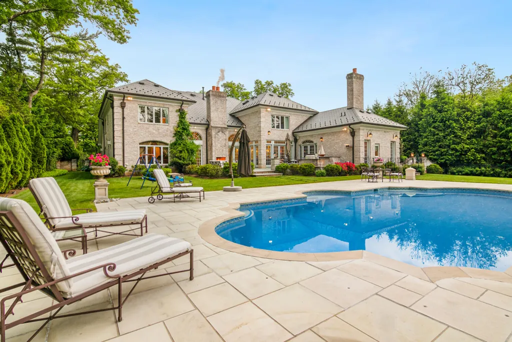 1 Lockhern Drive Home in Livingston Township, New Jersey. Step into the world of opulence with this custom-built, all-brick French Manor nestled on a tranquil cul-de-sac. The mature landscaping, saltwater pool, hot tub, limestone pool deck, and outdoor fireplace spanning 30 feet create a private oasis. Inside, discover a grand entrance hall leading to a stunning living room with a soaring 2-story ceiling, fireplace, and French doors opening to the patio and pool.