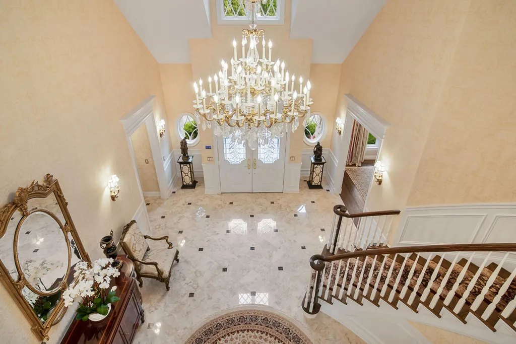 1 Lockhern Drive Home in Livingston Township, New Jersey. Step into the world of opulence with this custom-built, all-brick French Manor nestled on a tranquil cul-de-sac. The mature landscaping, saltwater pool, hot tub, limestone pool deck, and outdoor fireplace spanning 30 feet create a private oasis. Inside, discover a grand entrance hall leading to a stunning living room with a soaring 2-story ceiling, fireplace, and French doors opening to the patio and pool.