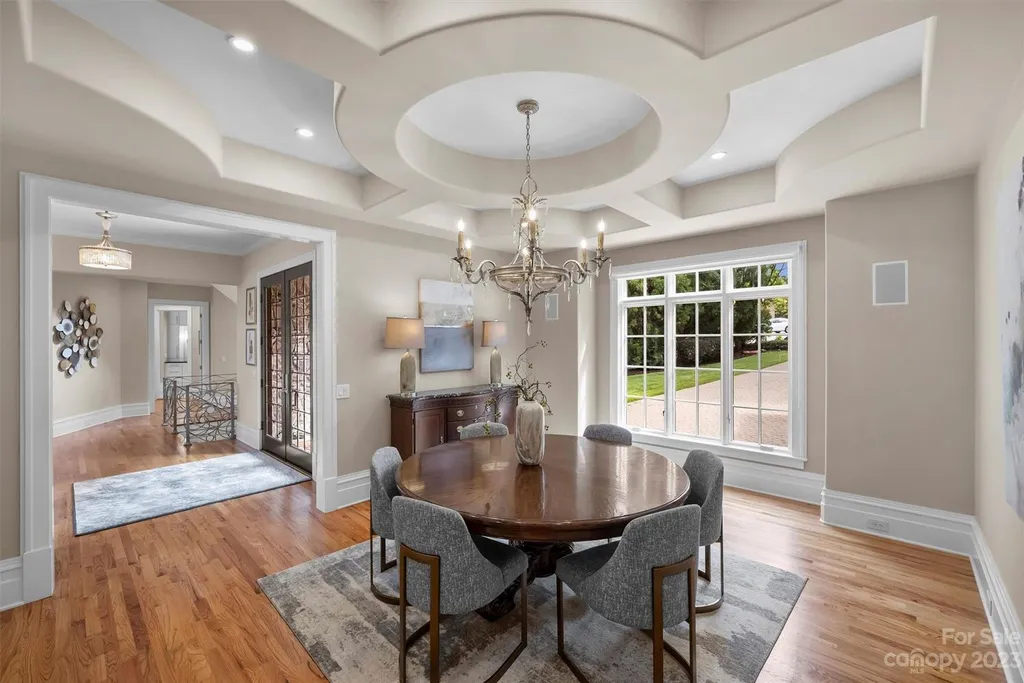 11717 Smart Lane Home in Charlotte, North Carolina. Experience the epitome of modern elegance in this gated estate with breathtaking views of the signature 13th hole from nearly every room and the stunning 48-ft pool. Designed by Christopher Phelps and crafted by Simonini, this home boasts an open floor plan, tall windows, curved walls, and a sweeping custom staircase inspired by Art Deco design.
