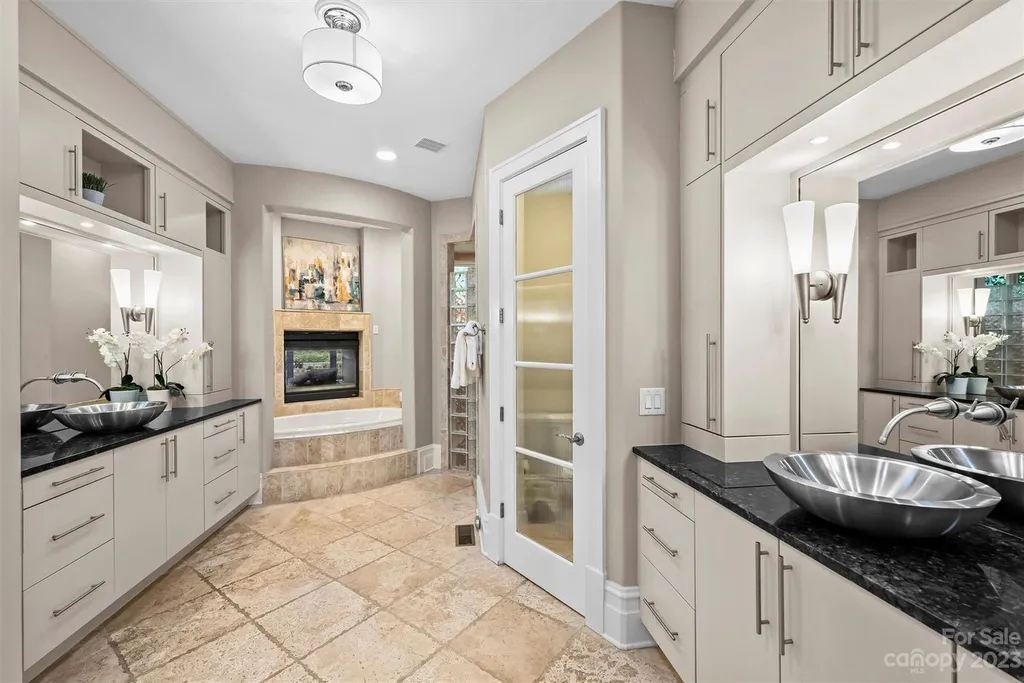 11717 Smart Lane Home in Charlotte, North Carolina. Experience the epitome of modern elegance in this gated estate with breathtaking views of the signature 13th hole from nearly every room and the stunning 48-ft pool. Designed by Christopher Phelps and crafted by Simonini, this home boasts an open floor plan, tall windows, curved walls, and a sweeping custom staircase inspired by Art Deco design.