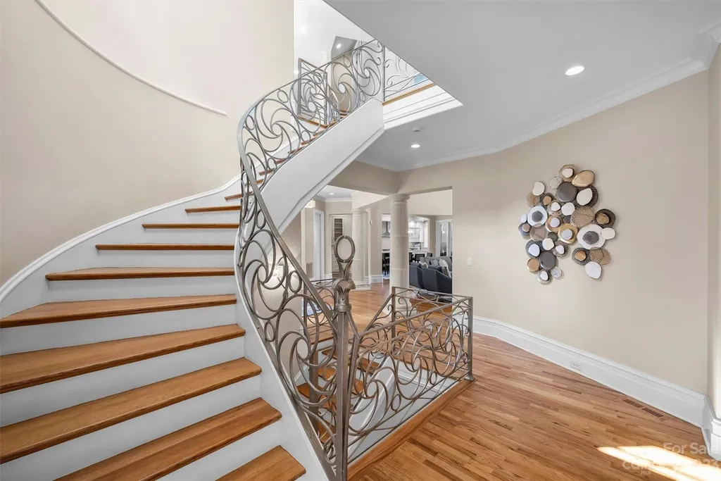 11717 Smart Lane Home in Charlotte, North Carolina. Experience the epitome of modern elegance in this gated estate with breathtaking views of the signature 13th hole from nearly every room and the stunning 48-ft pool. Designed by Christopher Phelps and crafted by Simonini, this home boasts an open floor plan, tall windows, curved walls, and a sweeping custom staircase inspired by Art Deco design.