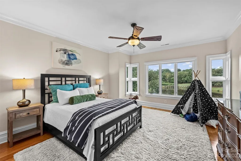 11717 Smart Lane Home in Charlotte, North Carolina. Experience the epitome of modern elegance in this gated estate with breathtaking views of the signature 13th hole from nearly every room and the stunning 48-ft pool. Designed by Christopher Phelps and crafted by Simonini, this home boasts an open floor plan, tall windows, curved walls, and a sweeping custom staircase inspired by Art Deco design.