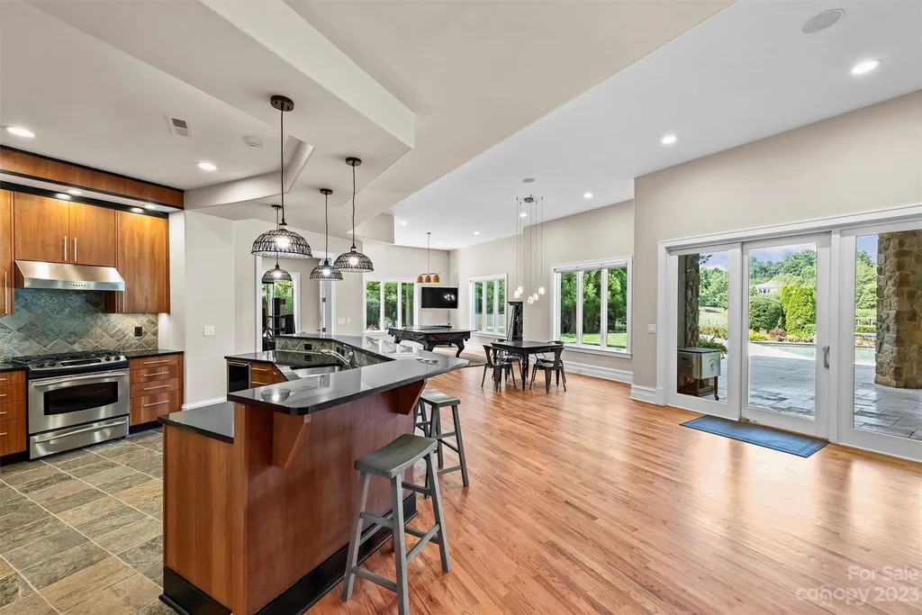 11717 Smart Lane Home in Charlotte, North Carolina. Experience the epitome of modern elegance in this gated estate with breathtaking views of the signature 13th hole from nearly every room and the stunning 48-ft pool. Designed by Christopher Phelps and crafted by Simonini, this home boasts an open floor plan, tall windows, curved walls, and a sweeping custom staircase inspired by Art Deco design.