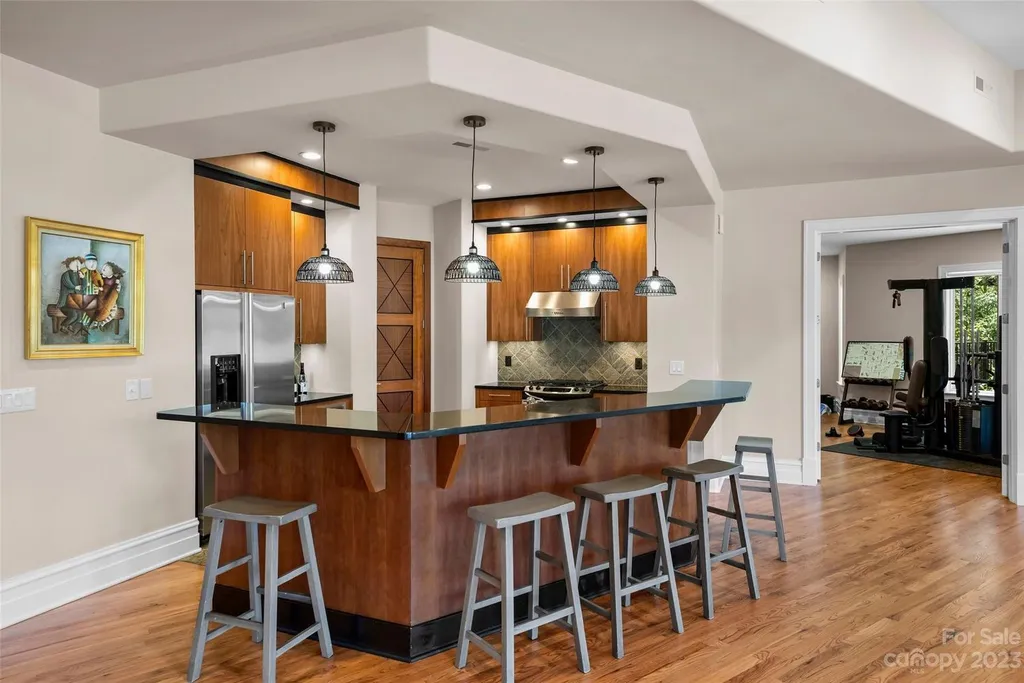11717 Smart Lane Home in Charlotte, North Carolina. Experience the epitome of modern elegance in this gated estate with breathtaking views of the signature 13th hole from nearly every room and the stunning 48-ft pool. Designed by Christopher Phelps and crafted by Simonini, this home boasts an open floor plan, tall windows, curved walls, and a sweeping custom staircase inspired by Art Deco design.
