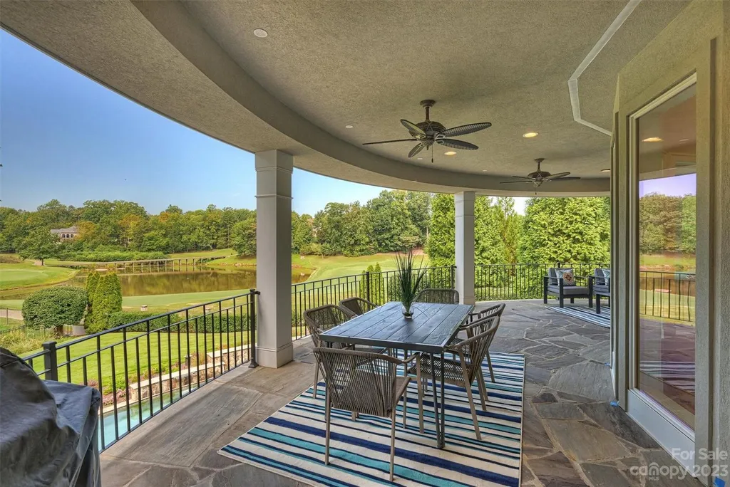 11717 Smart Lane Home in Charlotte, North Carolina. Experience the epitome of modern elegance in this gated estate with breathtaking views of the signature 13th hole from nearly every room and the stunning 48-ft pool. Designed by Christopher Phelps and crafted by Simonini, this home boasts an open floor plan, tall windows, curved walls, and a sweeping custom staircase inspired by Art Deco design.