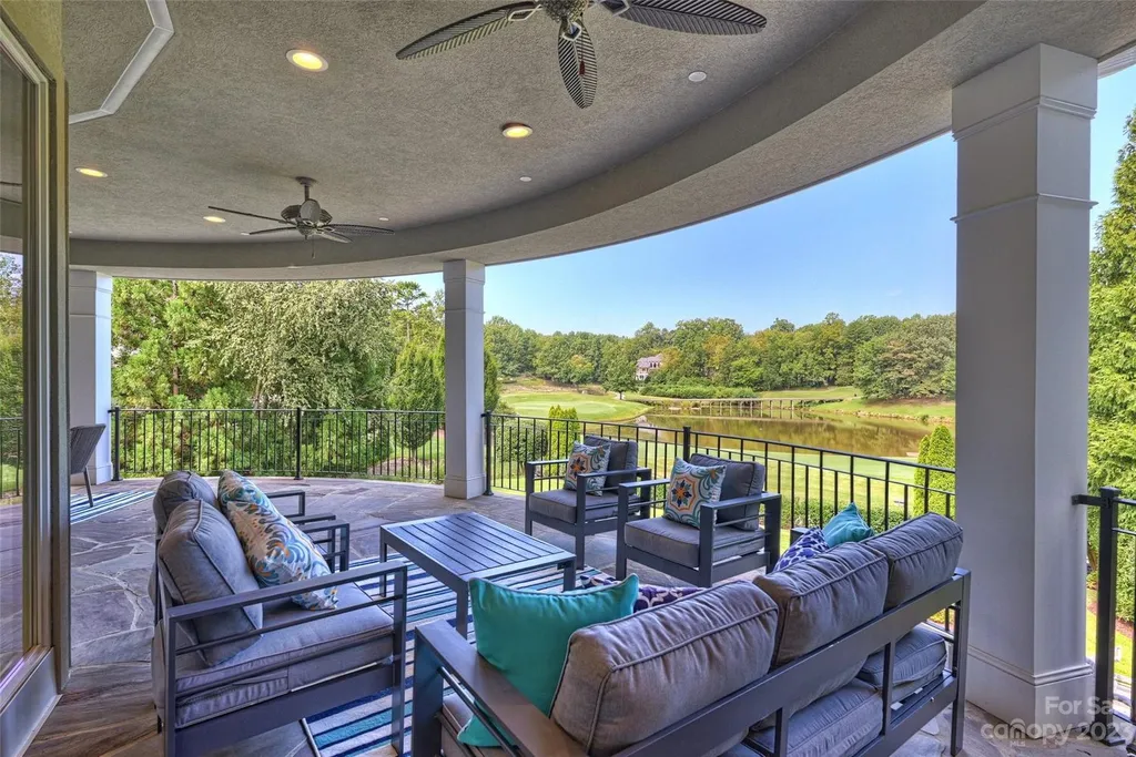 11717 Smart Lane Home in Charlotte, North Carolina. Experience the epitome of modern elegance in this gated estate with breathtaking views of the signature 13th hole from nearly every room and the stunning 48-ft pool. Designed by Christopher Phelps and crafted by Simonini, this home boasts an open floor plan, tall windows, curved walls, and a sweeping custom staircase inspired by Art Deco design.