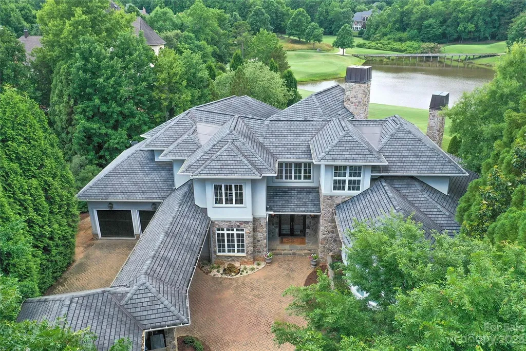 11717 Smart Lane Home in Charlotte, North Carolina. Experience the epitome of modern elegance in this gated estate with breathtaking views of the signature 13th hole from nearly every room and the stunning 48-ft pool. Designed by Christopher Phelps and crafted by Simonini, this home boasts an open floor plan, tall windows, curved walls, and a sweeping custom staircase inspired by Art Deco design.