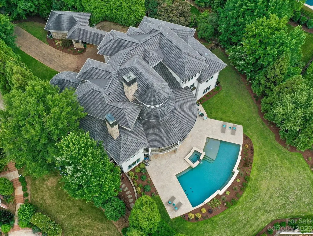11717 Smart Lane Home in Charlotte, North Carolina. Experience the epitome of modern elegance in this gated estate with breathtaking views of the signature 13th hole from nearly every room and the stunning 48-ft pool. Designed by Christopher Phelps and crafted by Simonini, this home boasts an open floor plan, tall windows, curved walls, and a sweeping custom staircase inspired by Art Deco design.