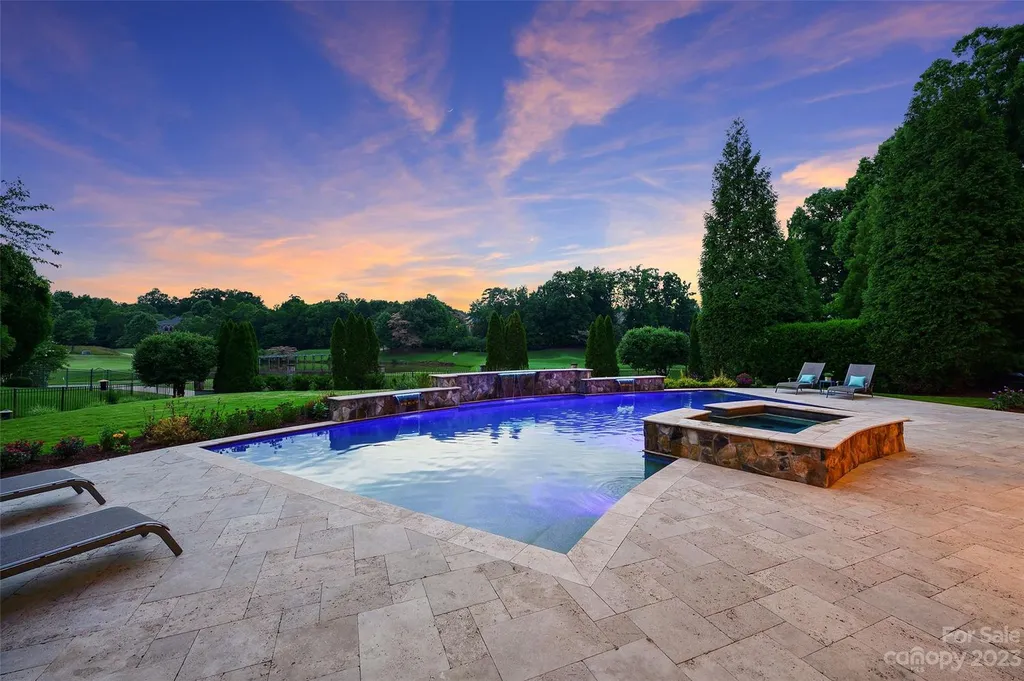 11717 Smart Lane Home in Charlotte, North Carolina. Experience the epitome of modern elegance in this gated estate with breathtaking views of the signature 13th hole from nearly every room and the stunning 48-ft pool. Designed by Christopher Phelps and crafted by Simonini, this home boasts an open floor plan, tall windows, curved walls, and a sweeping custom staircase inspired by Art Deco design.