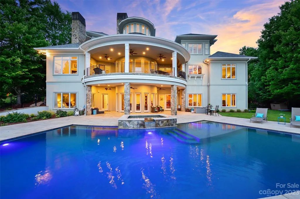 11717 Smart Lane Home in Charlotte, North Carolina. Experience the epitome of modern elegance in this gated estate with breathtaking views of the signature 13th hole from nearly every room and the stunning 48-ft pool. Designed by Christopher Phelps and crafted by Simonini, this home boasts an open floor plan, tall windows, curved walls, and a sweeping custom staircase inspired by Art Deco design.