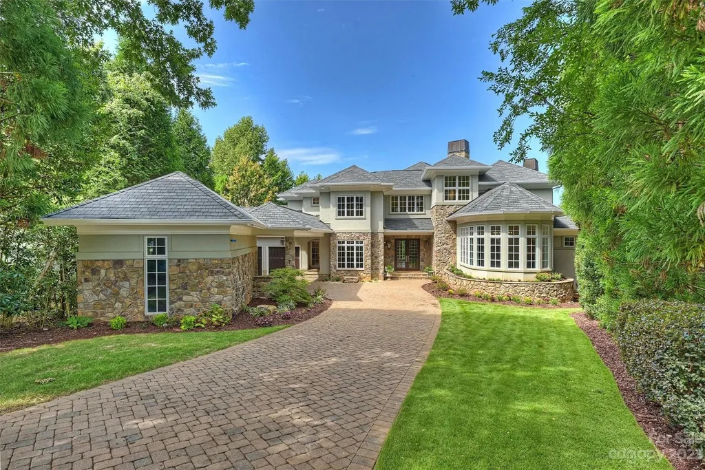 11717 Smart Lane Home in Charlotte, North Carolina. Experience the epitome of modern elegance in this gated estate with breathtaking views of the signature 13th hole from nearly every room and the stunning 48-ft pool. Designed by Christopher Phelps and crafted by Simonini, this home boasts an open floor plan, tall windows, curved walls, and a sweeping custom staircase inspired by Art Deco design.
