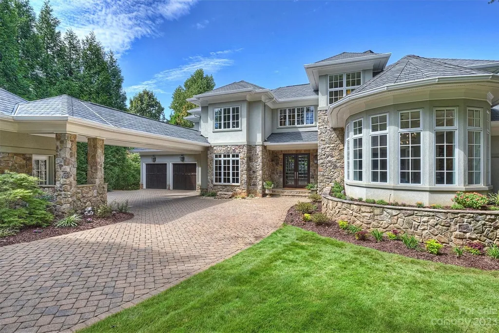 11717 Smart Lane Home in Charlotte, North Carolina. Experience the epitome of modern elegance in this gated estate with breathtaking views of the signature 13th hole from nearly every room and the stunning 48-ft pool. Designed by Christopher Phelps and crafted by Simonini, this home boasts an open floor plan, tall windows, curved walls, and a sweeping custom staircase inspired by Art Deco design.