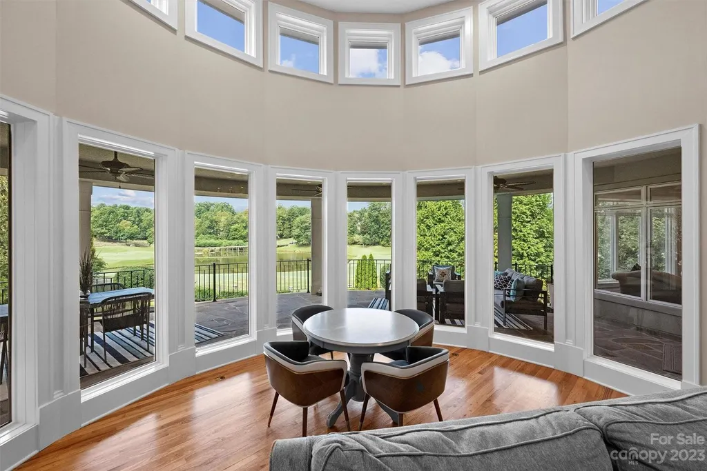 11717 Smart Lane Home in Charlotte, North Carolina. Experience the epitome of modern elegance in this gated estate with breathtaking views of the signature 13th hole from nearly every room and the stunning 48-ft pool. Designed by Christopher Phelps and crafted by Simonini, this home boasts an open floor plan, tall windows, curved walls, and a sweeping custom staircase inspired by Art Deco design.
