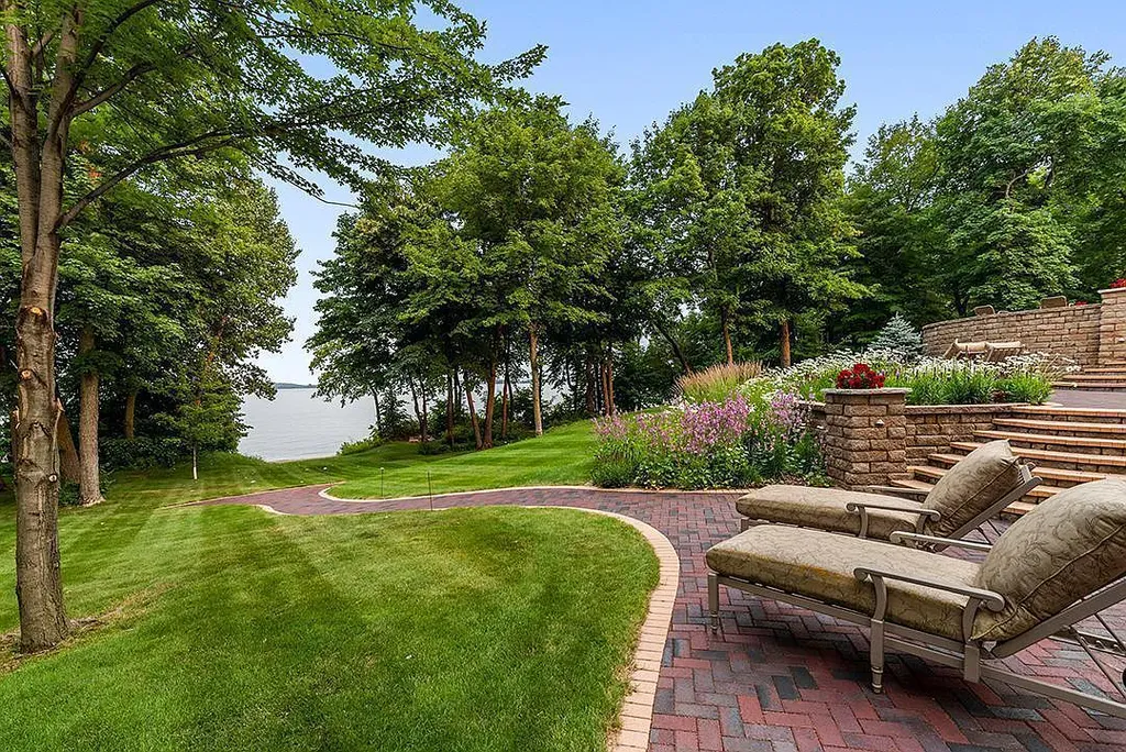 This stunning lakefront home is located in Cormorant Park Place, a premier lakeshore community. It has 6 bedrooms, 5 bathrooms, and 9,595 square feet of living space. The home features soaring ceilings, grand windows, hand-hewn imported wood, and hand-picked stone surfaces. It also has a private terrace with a fire pit, and access to the community's amenities, including a clubhouse, heated pool, swim beach, and slip system.
