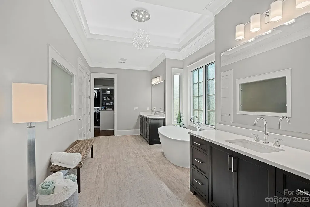 This stunning home in Providence Downs South offers luxury resort living with spa-like amenities, perfect for entertaining and relaxing. It has 5 bedrooms, 4 full baths, and 3 half baths, plus a 4-car garage with epoxy floor. The kitchen has a huge island with Wolf & Subzero appliances, and the backyard has a heated pool, hot tub, and pool house with sauna. 