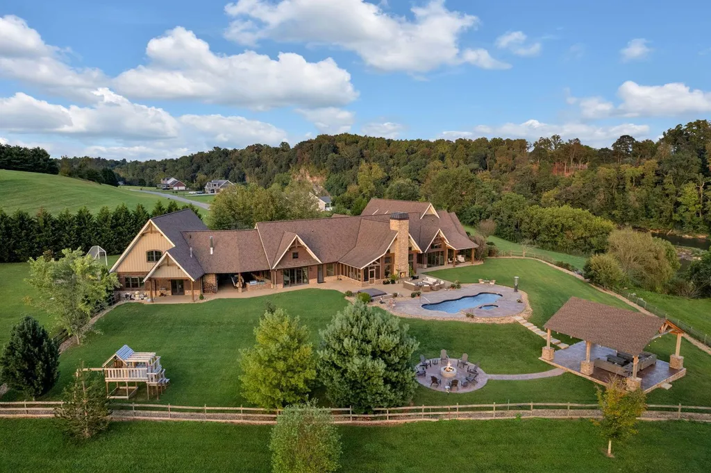 180 Riverwalk Court Home in Greeneville, Tennessee. Discover your dream oasis on this breathtaking 5-acre riverfront property! This extraordinary 7,000+ sqft home seamlessly blends transitional architecture with rustic charm, creating a captivating retreat. The striking blend of stone and poplar wood siding on the exterior exudes warmth and charm.