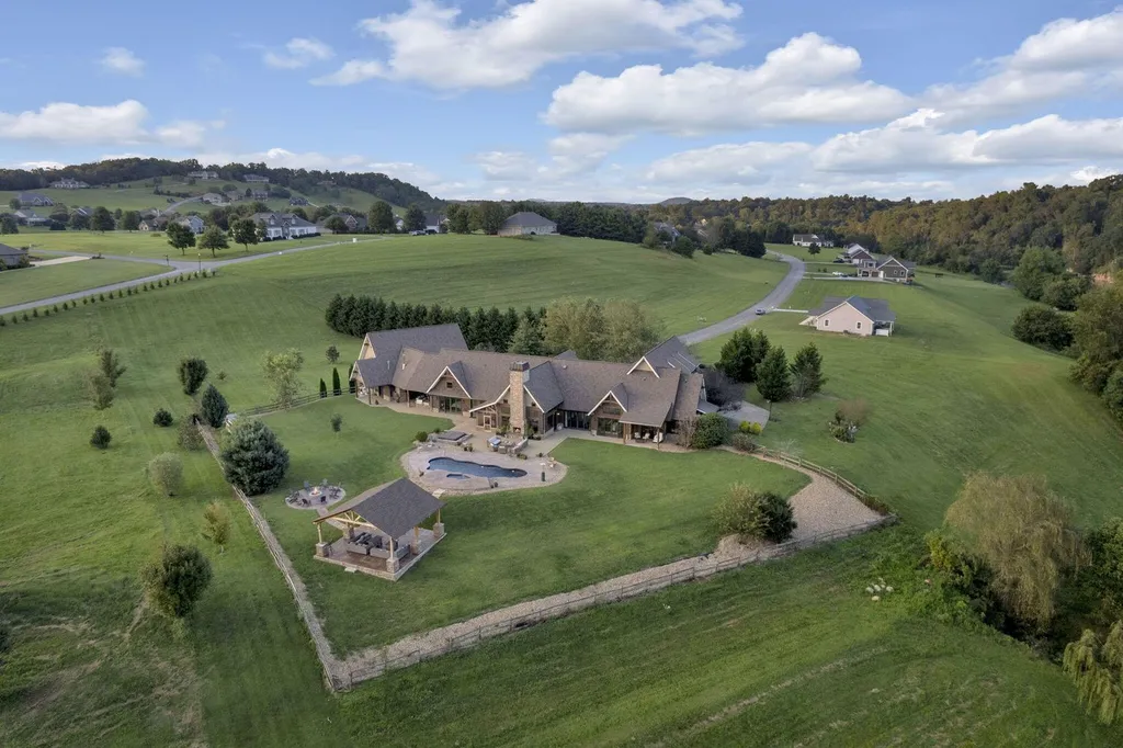 180 Riverwalk Court Home in Greeneville, Tennessee. Discover your dream oasis on this breathtaking 5-acre riverfront property! This extraordinary 7,000+ sqft home seamlessly blends transitional architecture with rustic charm, creating a captivating retreat. The striking blend of stone and poplar wood siding on the exterior exudes warmth and charm.
