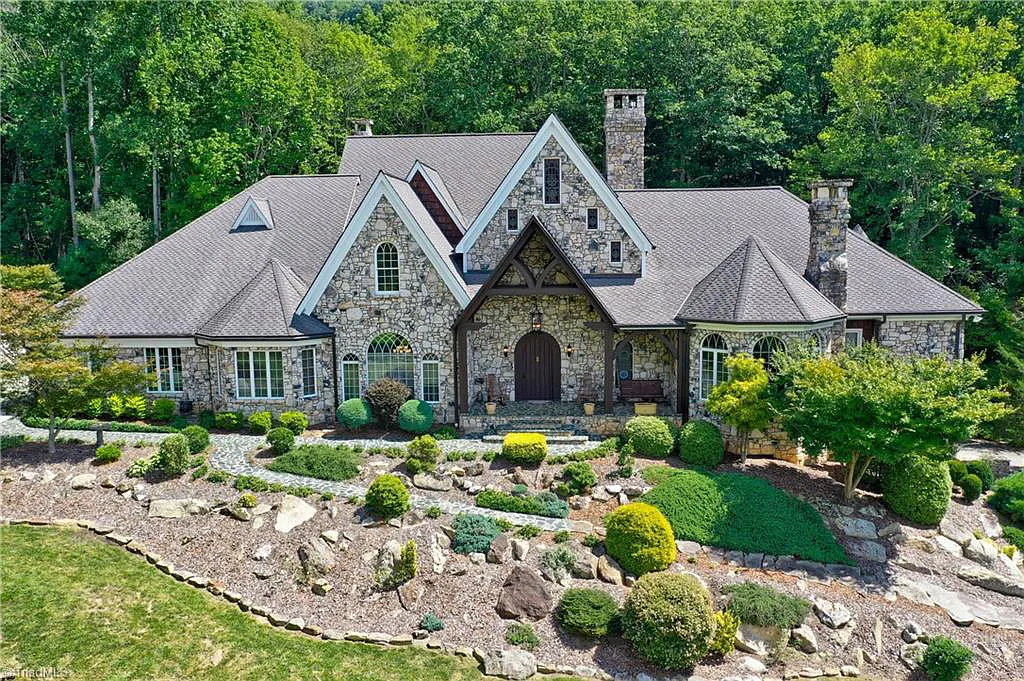 5712 Summit Road Home in Purlear, North Carolina. Explore this exceptional 128+ acre mountain retreat with a gated entrance, a timber-frame home boasting 5 bedrooms and 5 bathrooms. Enjoy the beauty of two spring-fed creeks that encircle the fieldstone exterior of the home.