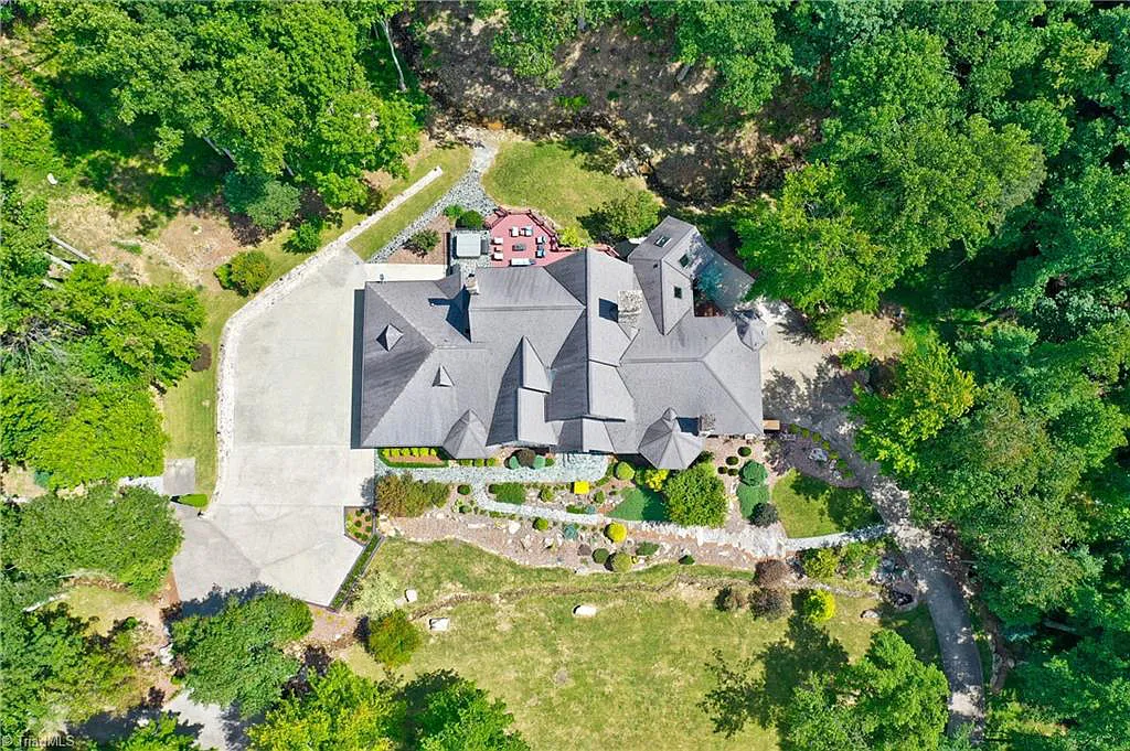 5712 Summit Road Home in Purlear, North Carolina. Explore this exceptional 128+ acre mountain retreat with a gated entrance, a timber-frame home boasting 5 bedrooms and 5 bathrooms. Enjoy the beauty of two spring-fed creeks that encircle the fieldstone exterior of the home.