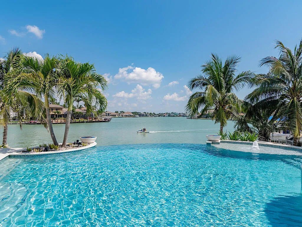 Discover your dream home at 1340 Caxambas Ct, Marco Island, Florida! This 5-bed, 5-bath luxury residence with a theater room boasts 5,007 sq ft of impeccable craftsmanship, situated on 0.59 acres with 248 ft of water frontage and a newer seawall, ensuring endless views and quick access to Caxambas Pass.