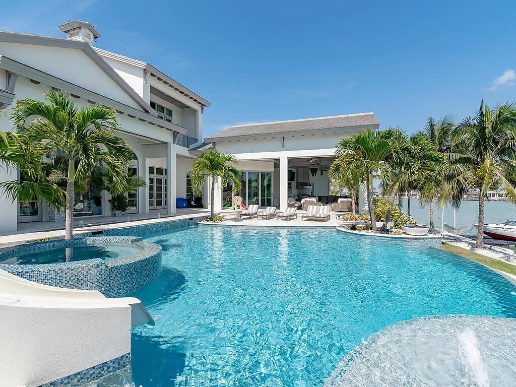 Discover your dream home at 1340 Caxambas Ct, Marco Island, Florida! This 5-bed, 5-bath luxury residence with a theater room boasts 5,007 sq ft of impeccable craftsmanship, situated on 0.59 acres with 248 ft of water frontage and a newer seawall, ensuring endless views and quick access to Caxambas Pass.
