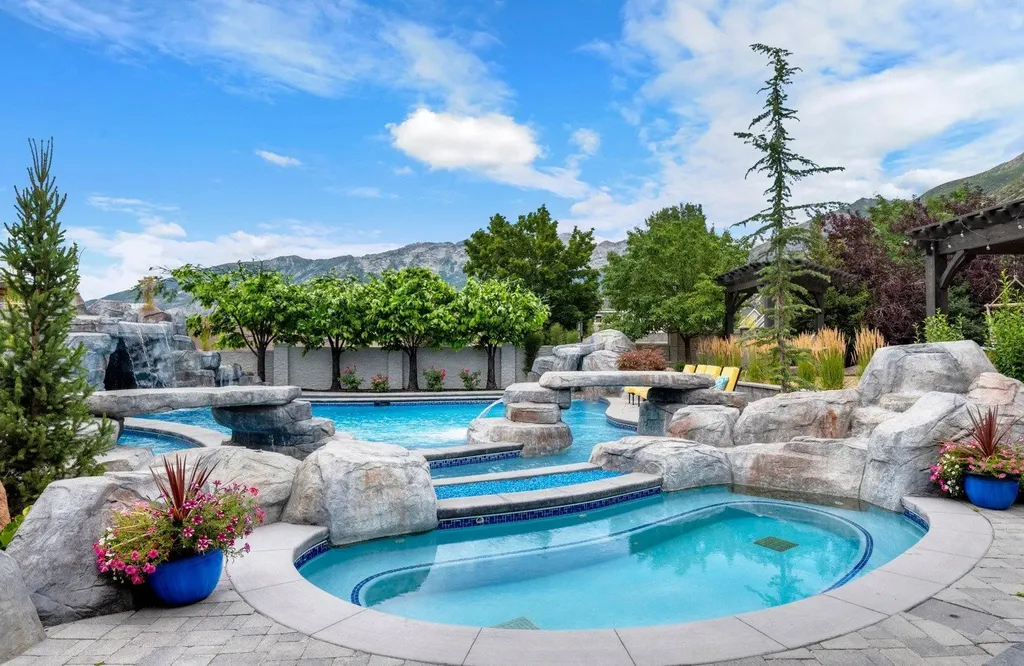 1263 East Chapman Court Home in Alpine, Utah. Step into the lap of luxury in this expansive 13,000 sq ft home in Alpine, Utah. With 8 oversized bedrooms, 6 bathrooms, a 13-car garage, and an outdoor entertainment paradise featuring a pool, spa, and lush landscaping, this property is perfect for hosting and living in grand style.